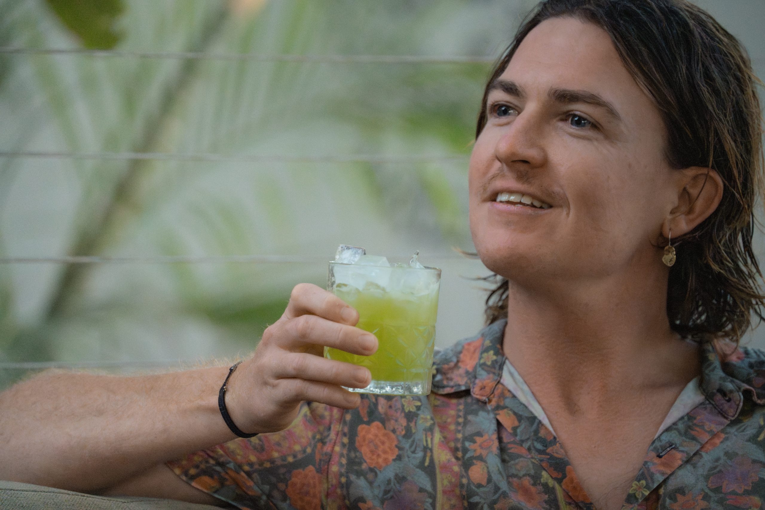 Refreshing Mocktail at Mutts Café Guy holding a colorful mocktail, smiling, sunset and sunny summer vibes at Mutts Café. Drinks Menu Exmouth