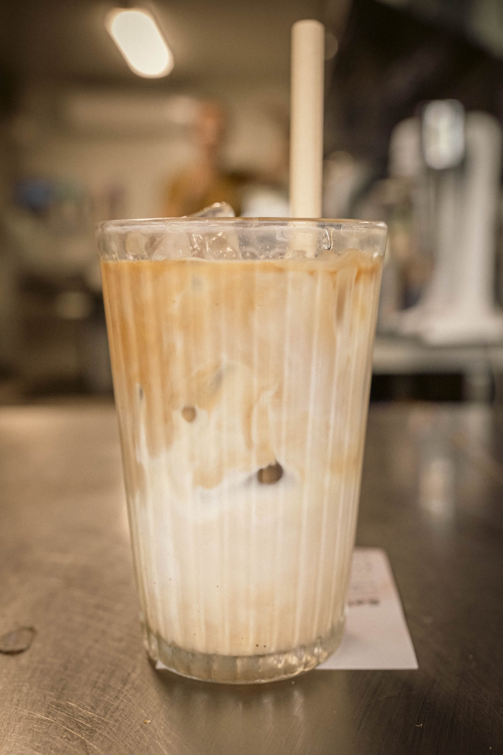 Iced Latte at Mutts Café Close-up of iced latte served in a glass with ice, sitting on a bench outside at Mutts Café. Drinks Menu Exmouth