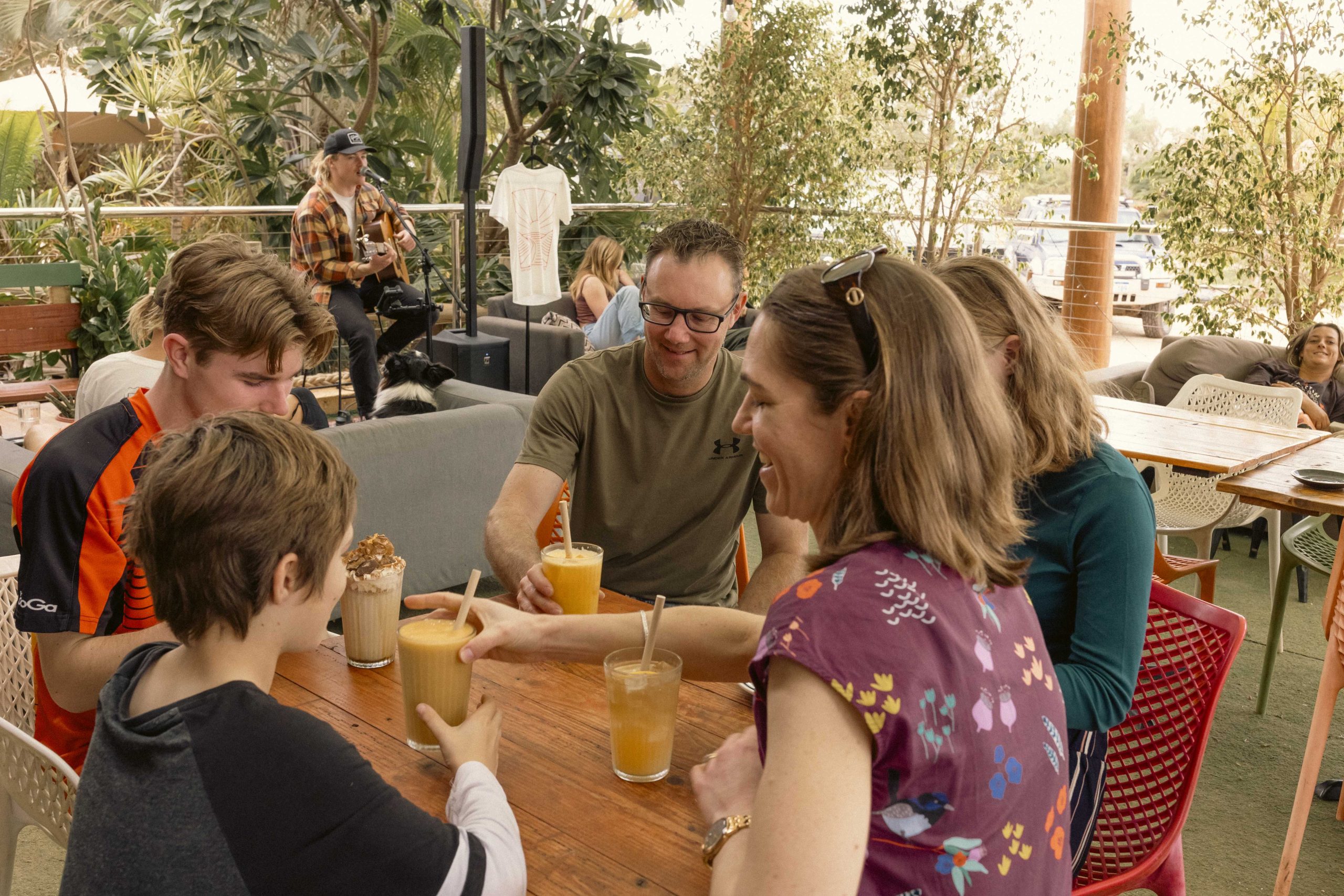 Family Drinks at Mutts Café Outdoor Area Family enjoying a variety of drinks at Mutts Café’s outdoor seating, with tables of happy customers and live music in the background on a sunny day. Drinks Menu Exmouth