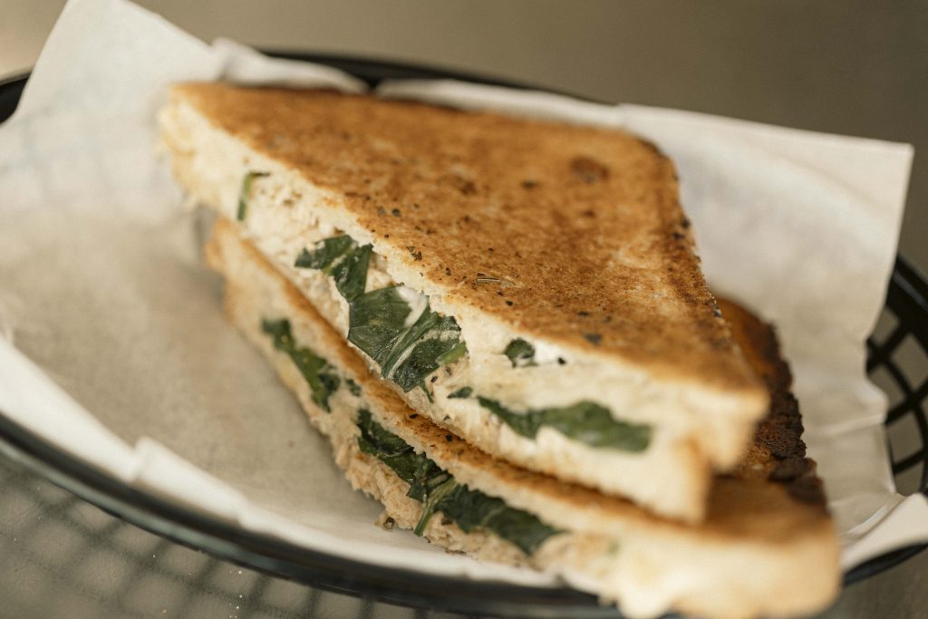 Toasted Chicken Toastie | Mutts Café Exmouth Close-up of a toasted chicken toastie with melted cheese and spinach at Mutts Café Exmouth.
