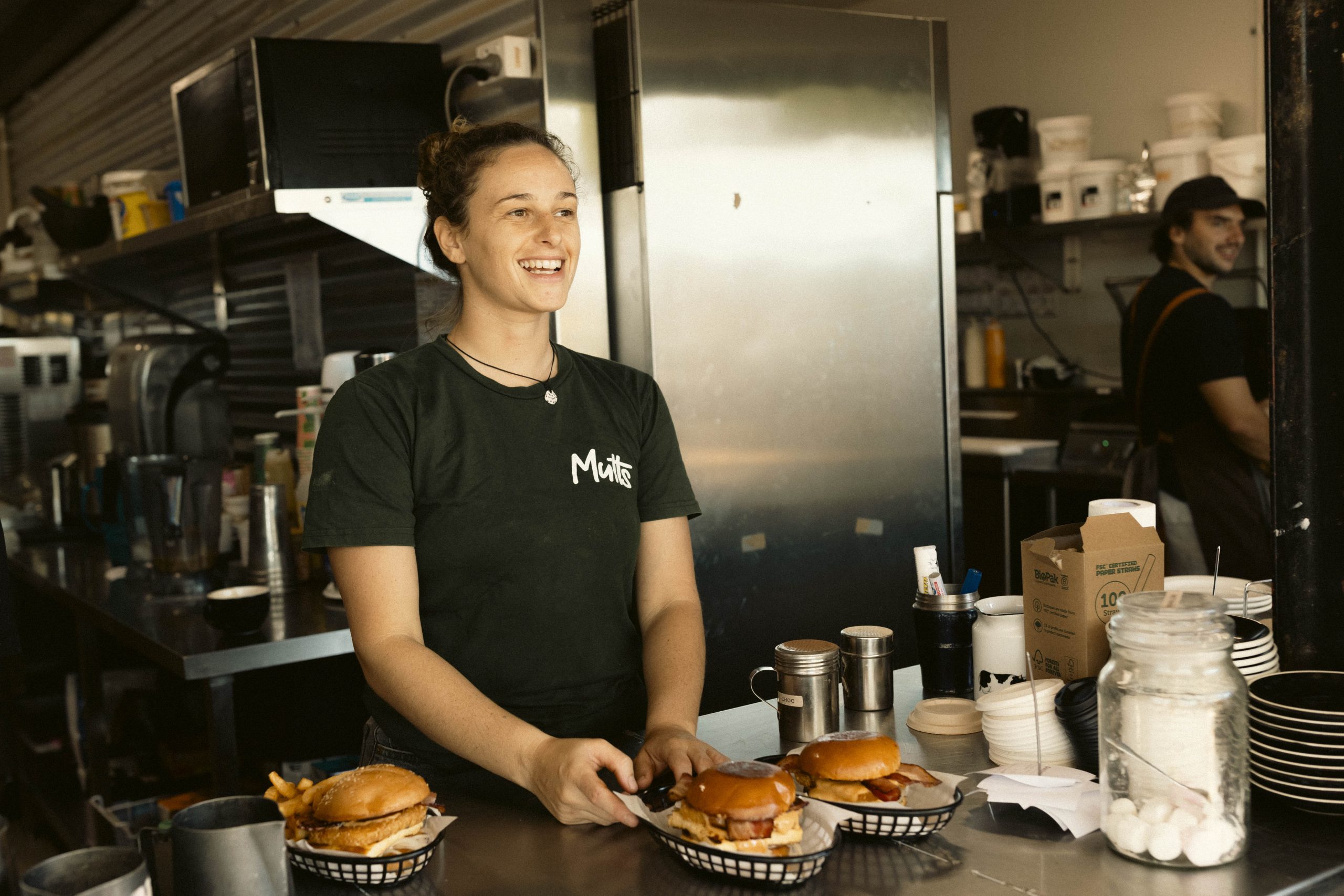 Smiling staff member passing burgers through the service window at Mutts Café Exmouth Hospitality jobs Exmouth WA.